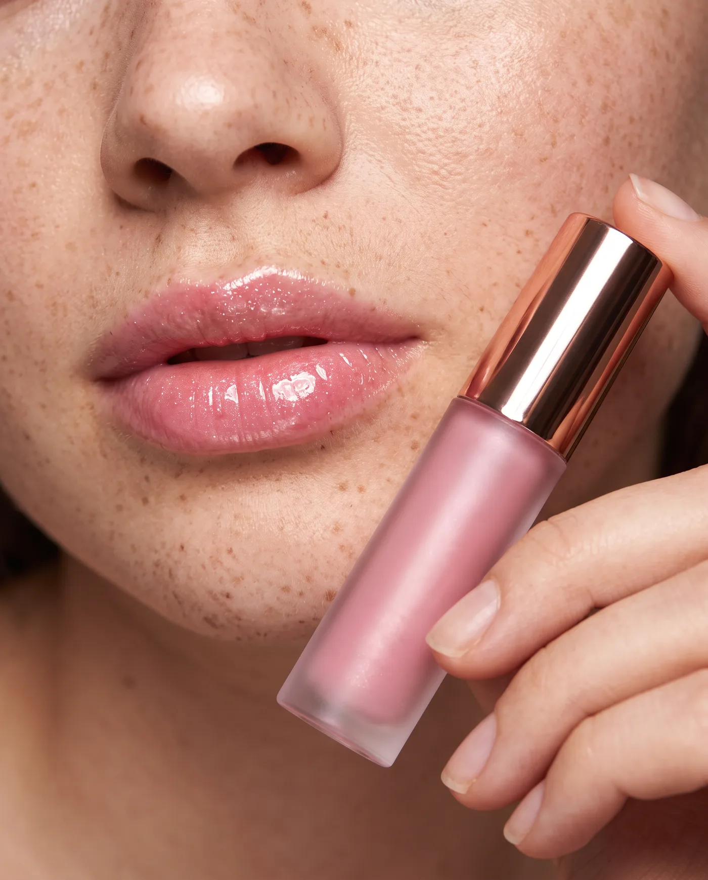 Beauty close-up of glossy pink lips with a frosted lip gloss tube